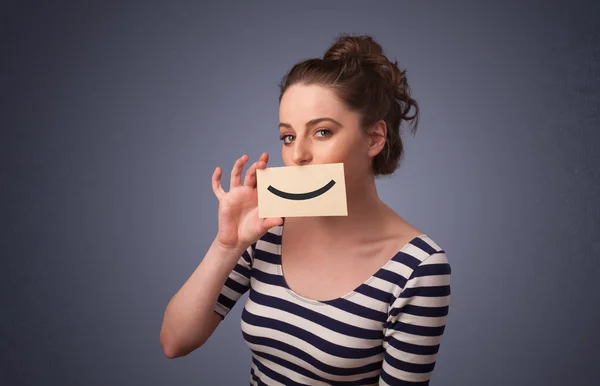 Happy pretty woman holding card with funny smiley — Stock Photo, Image