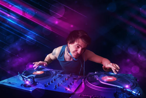 Young DJ playing on turntables with color light effects — Stock Photo, Image