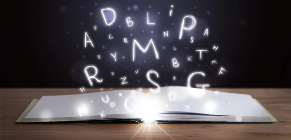 Open book with glowing letters flying out — Stock Photo, Image