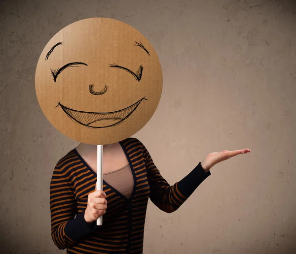 Young woman holding a smiley face board — Stock Photo, Image