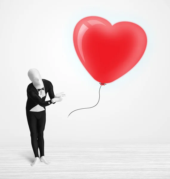 Lindo tipo en traje de cuerpo morpsuit mirando un corazón en forma de globo —  Fotos de Stock