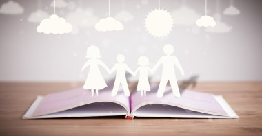 Ailenin karton figürleri açık bir kitabın üzerinde.