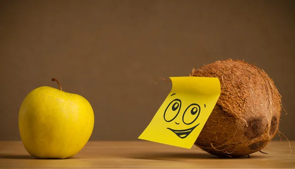 Coconut with post-it note looking at apple — Stock Photo, Image