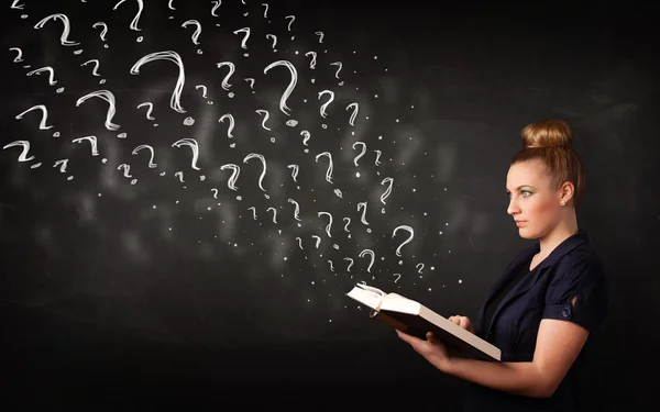 Pretty woman reading a book with question marks coming out from — Stock Photo, Image