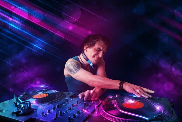 Молодой DJ играет на проигрывателях с цветовыми световыми эффектами — стоковое фото