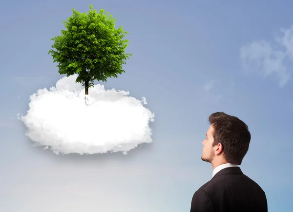 Jovem apontando para uma árvore verde em cima de uma nuvem branca — Fotografia de Stock