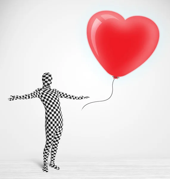 Cute guy in morpsuit body suit looking at a balloon shaped heart — Stock Photo, Image