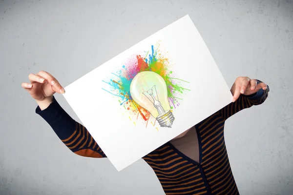 Woman holding a cardboard with paint splashes and lightbulb in f — Stock Photo, Image