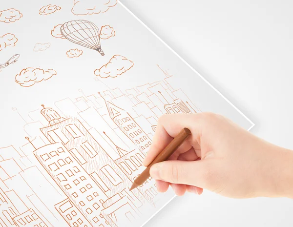 A person drawing sketch of a city with balloons and clouds on a — Stock Photo, Image