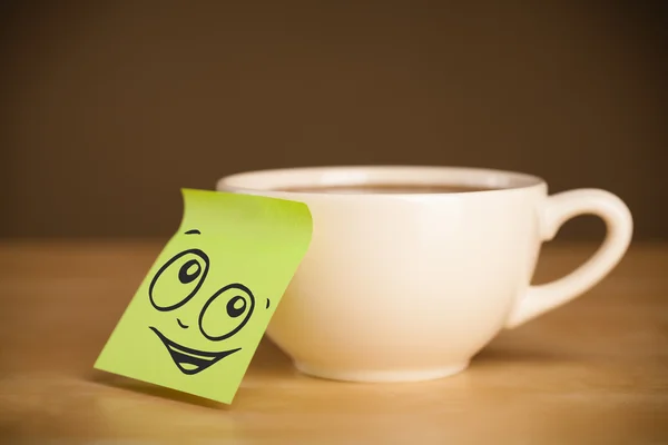 Nota post-it con la cara sonriente pegada en la taza — Foto de Stock