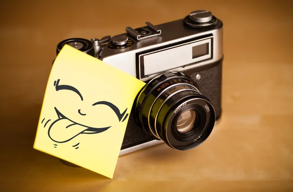 Post-it notera med smiley ansikte klistras på fotokamera — Stockfoto