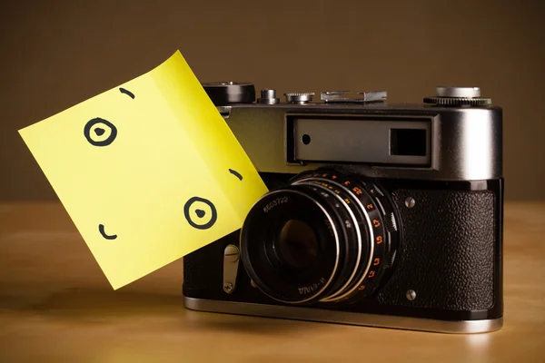 Post-it opmerking met smileygezicht gevezen op een fotocamera — Stockfoto