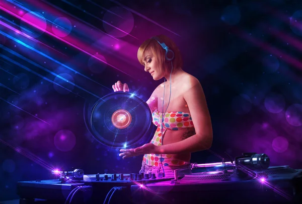 Young DJ playing on turntables with color light effects — Stock Photo, Image