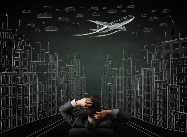 Businessman sitting in front of a cityscape drawing on a chalkbo — Stock Photo, Image