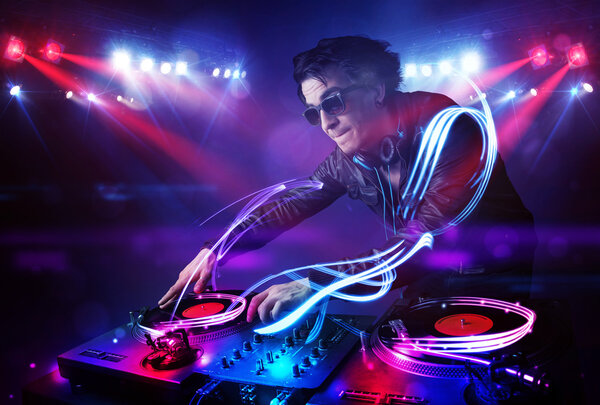 Disc jockey playing music with light beam effects on stage