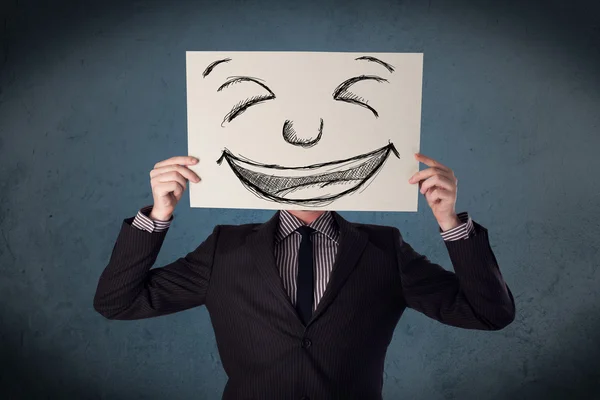 Empresário segurando um papel com rosto sorridente na frente de sua hea — Fotografia de Stock