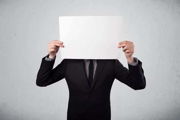 Businessman holding in front of his head a paper with copy space — Stock Photo, Image