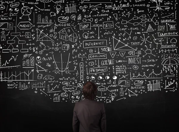 Businessman standing in front of drawn charts on a blackboard — Stock Photo, Image