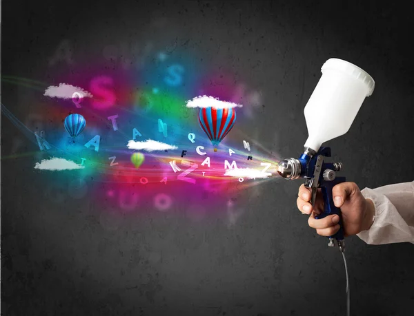 Worker with airbrush and colorful abstract clouds and balloons — Stock Photo, Image