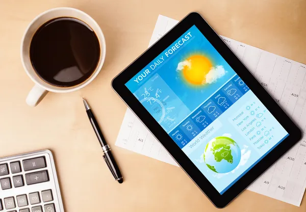 Tablet pc showing weather forecast on screen with a cup of coffe — Stock Photo, Image