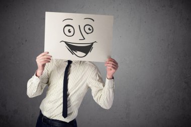 empresario sosteniendo una cartulina con cara sonriente en él en frente
