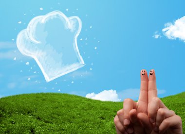 Mutlu gülen yüzlü parmaklar aşçı şapkasının resmine bakıyor.