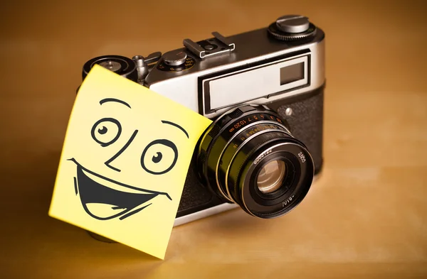Post-it notera med smiley ansikte klistras på fotokamera — Stockfoto