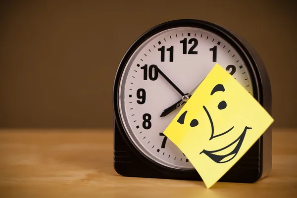 Nota post-it con la cara sonriente pegada en un reloj —  Fotos de Stock