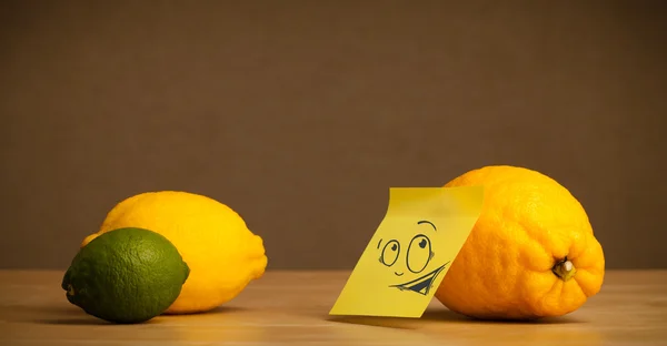 Lemon with post-it note looking curiously at citrus fruits — Stock Photo, Image