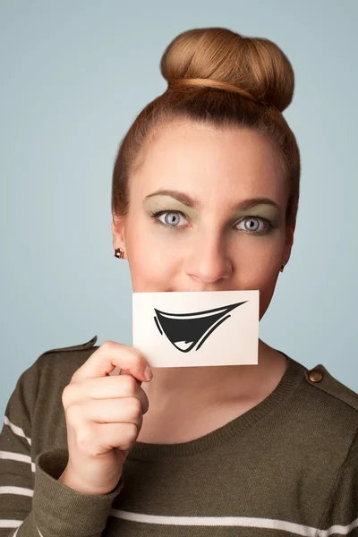 Happy cute girl holding paper with funny smiley drawing — Stock Photo, Image