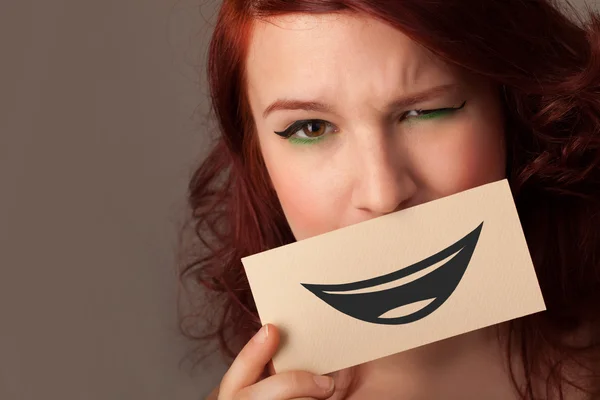 Happy pretty woman holding card with funny smiley — Stock Photo, Image