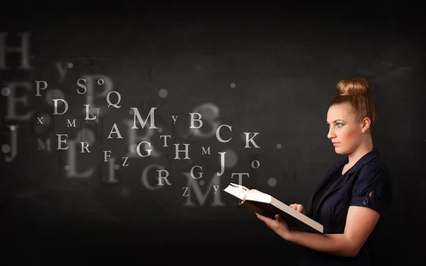 Giovane signora che legge un libro con lettere alfabetiche — Foto Stock