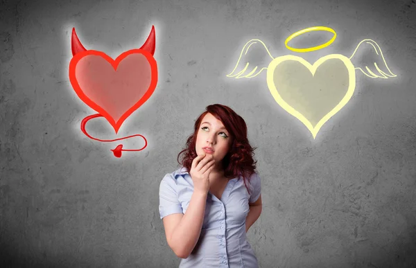 Woman standing between the angel and devil hearts — Stock Photo, Image