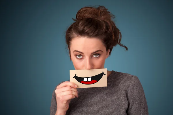 Happy pretty woman holding card with funny smiley — Stock Photo, Image