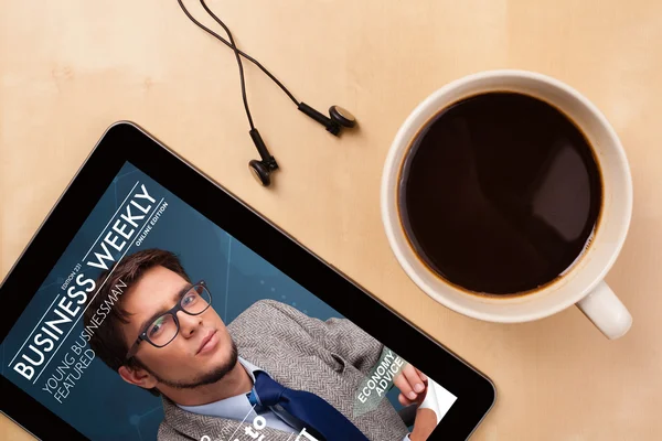 Tablet pc che mostra rivista sullo schermo con una tazza di caffè su un d — Foto Stock