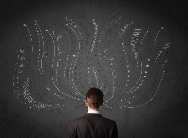 Businessman thinking with sketched arrows in front of a chalkboa — Stock Photo, Image