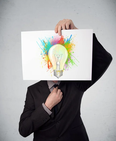 Empresario sosteniendo un cartón con salpicaduras de pintura y lightbul — Foto de Stock