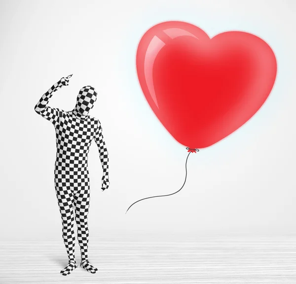 Leuke kerel in morpsuit body suit kijken naar een ballon vormige hart — Stockfoto