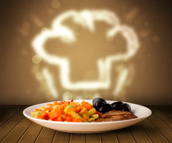 Delicious food plate with chef cook hat — Stock Photo, Image
