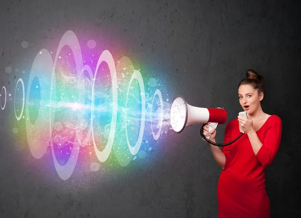 Young girl yells into a loudspeaker and colorful energy beam com — Stock Photo, Image