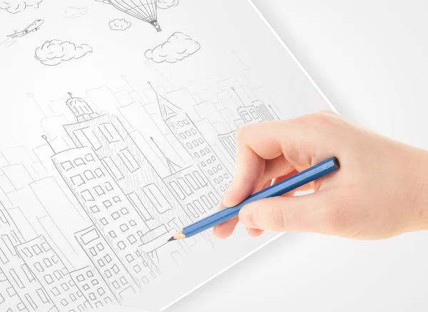 A person drawing sketch of a city with balloons and clouds on a — Stock Photo, Image