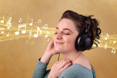 Kulaklıklı genç bir kadın müzik dinliyor.
