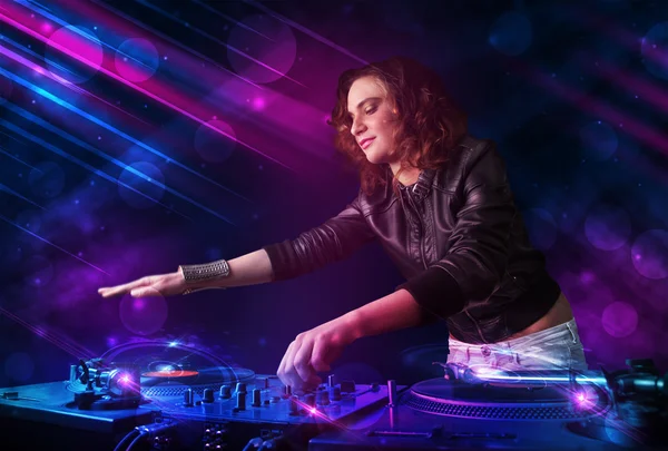 Young DJ playing on turntables with color light effects — Stock Photo, Image