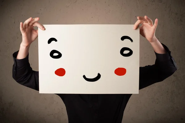 Businessman holding a cardboard with a smiley face on it — Stock Photo, Image