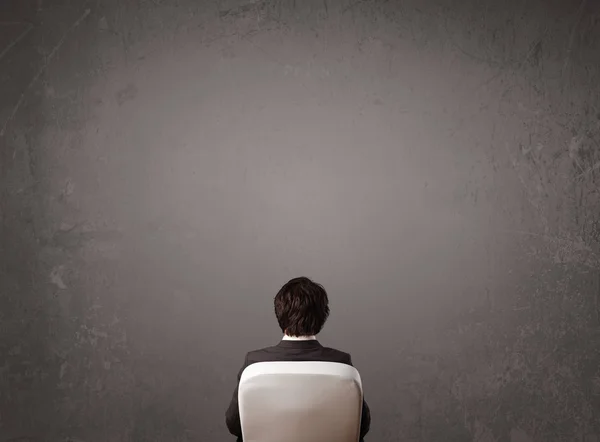 Бизнесмен сидит перед стеной с копировальным пространством — стоковое фото