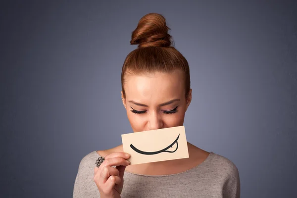 Chica bastante joven sosteniendo la tarjeta blanca con dibujo sonrisa —  Fotos de Stock