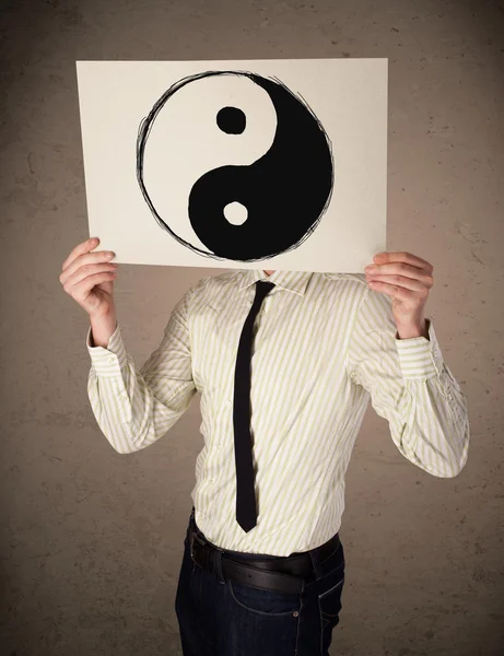 Businessman holding a paper with a yin-yang on it in front of hi — Stock Photo, Image