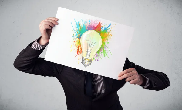 Podnikatel držící lepenky s barvou šplouchá a lightbul — Stock fotografie