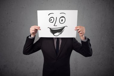 empresario sosteniendo una cartulina con cara sonriente en él en frente
