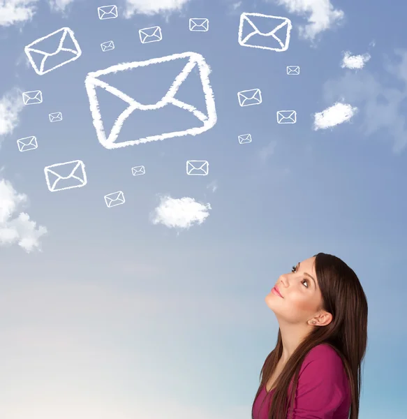 Chica joven mirando el símbolo de correo nubes en el cielo azul —  Fotos de Stock